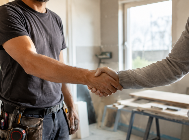 Un artisan et son client se serrent la main sur un chantier.